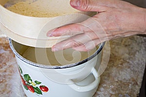 Flour is sifted through a wooden sieve