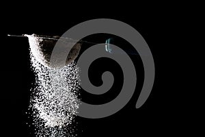 Flour sifting on a black background. White powder sift isolated on black background