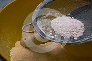 Flour sifting through a metal sieve for a baking. Close up