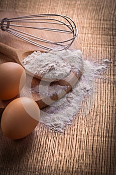 Flour in spoon eggs corolla on vintage wooden
