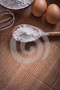 Flour in sppon corolla eggs on vintage wooden