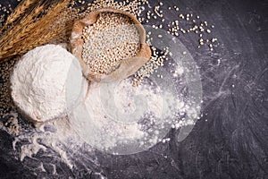 Flour and wheat grains in sacks with wheat ears On a black background table. In a rustic kitchen. Top view