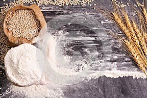 Flour and wheat grains in sacks with wheat ears On a black background table. In a rustic kitchen. Top view