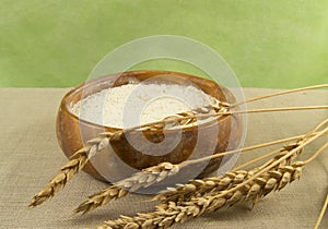 Flour in a wooden bowl with ears of wheat