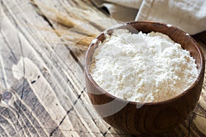 Flour in wooden bowl and wheat ears on wooden background. Copy space