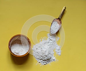 Floured flour on a yellow background, a copper pot of flour and a cooking scoop, horizontal