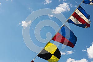 Flourishing flags flying against a blue sky with white clouds