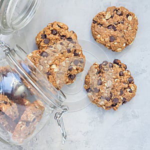 Flourless gluten free peanut butter, oatmeal and chocolate chips cookies in glass jar, top view, square