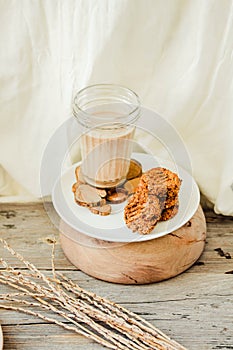 Flourless gluten free peanut butter, oatmeal and date with a glass of milk on a wooden background. Copy space