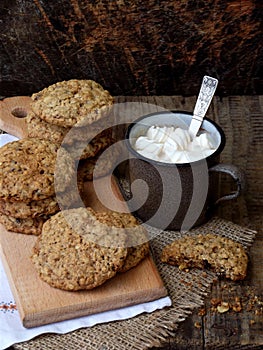 Flourless gluten free peanut butter, oatmeal, dried fruits cookies and cup of cocoa with marshmallows on wooden background. Vertic