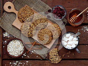 Flourless gluten free peanut butter, oatmeal, honey, dried fruits cookies and cup of cocoa with marshmallows on wooden background.