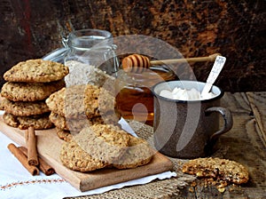 Flourless gluten free peanut butter, oatmeal, honey, dried fruits cookies and cup of cocoa with marshmallows on wooden background.