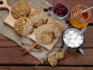 Flourless gluten free peanut butter, oatmeal, honey, dried fruits cookies and cup of cocoa with marshmallows on wooden background.