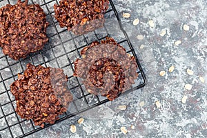 Flourless no bake peanut butter and oatmeal chocolate cookies on a cooling rack, horizontal, top view, copy space