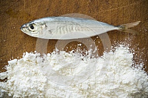 Floury fish on a wooden background