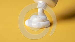 A white toothpaste tube is shown expelling a perfect dollop of white toothpaste