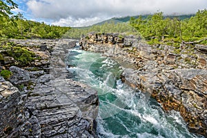 The flow of Abiskojokk river through the rocky canyon in Abisko National park in Northern Sweden
