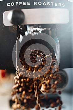 The flow of coffee beans from open flap of the cooling mixer of roasting machine