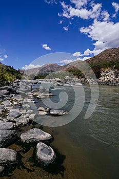 .flow of the santa river with circular stones in the foreground and mountains in the background photo