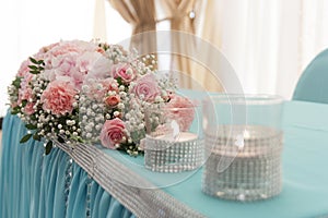 Flower arrangement in delicate colors is on the table for the newlyweds in the restaurant