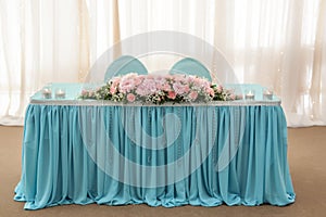 Flower arrangement in delicate colors is on the table for the newlyweds in the restaurant