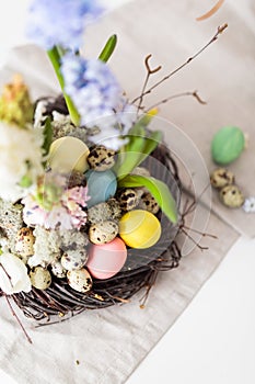 Flower arrangement in a nest with easter eggs on a white table