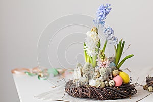 Flower arrangement in a nest with easter eggs on a white table