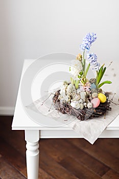 Flower arrangement in a nest with easter eggs on a white table