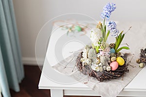 Flower arrangement in a nest with easter eggs on a white table