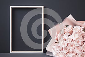 Flower arrangement. Pink flowers, white photo frame on pastel gray background. Copy space