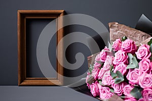 Flower arrangement. Pink flowers, wooden brown photo frame on pastel gray background, copy space