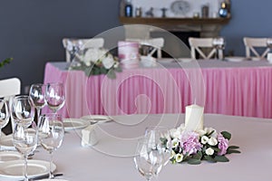 Flower arrangement in pink with white candles on the festive table on the wedding day.