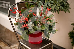flower arrangement in pot of spruce branches and red berries and eucalyptus