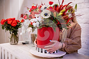 A flower arrangement in red shades of orchids, roses, sunflowers, lilies, alstroemerias and ornithogalums in a red box in the