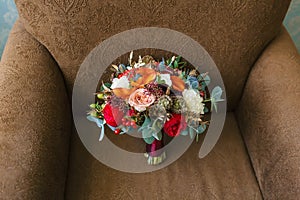 Flower arrangement for a wedding party. The bouquet of pink roses, red peonies and other flowers on brown armchair