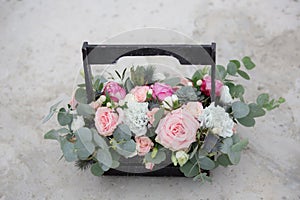 Flower arrangement in a wooden box with spray pink roses, succulent, eustoma, white hypericum, eucaliptus