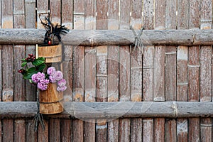 Flower in bamboo vase hanging on bamboo fence background - Japanese Ikebana