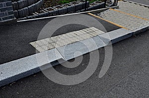 A flower bed at an intersection with curved curbs. Pedestrians pass