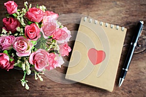 Flower with blank notepad and pen on old wooden background