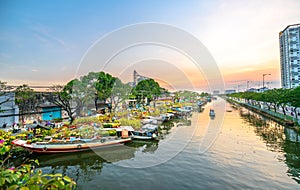 Flower boats full of flowers parked along canal wharf in sunset