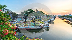 Flower boats full of flowers parked along canal wharf in sunset