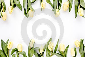 Flower border frame made of yellow and beige buds tulip on a white background. The apartment lay, top view. Floral