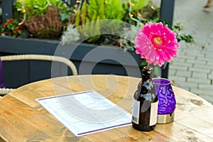 Flower in a bottle, candle and menus on the table