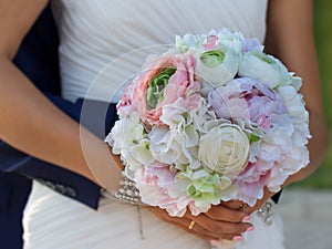 Flower bouqet in hands of bride which groom embracing