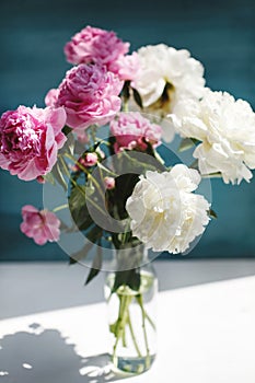 Flower bouquet of pink natural peonies flowers in a vase in sunshine