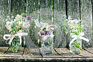 Flower bouquets in glass jars on rustic wood background