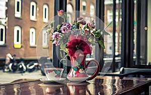 Flower in a ceramic vase with a coffee cup.