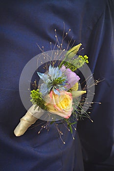 Flower clip for groom attached to pocket of dark blue shirt made from beautiful natural roses and wild flowers