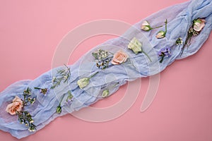 Flower composition on pink background, rose buds, eustoma, limonium inflorescences on blue gauze, copy space