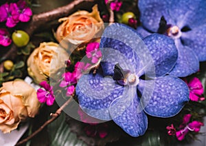 Flower composition with purple orchid flowers and soft orange roses